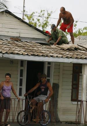 SOME DAMAGE: Two men work diligently to repair a roof of a house in Santa Cruz del Sur, in Camaguey, on Tuesday.   More photos