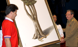 Julio Martinez presents Army General Raul Castro with a painting.