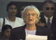 Janet Jagan reading to a crowd from a stack of papers in her hand. 